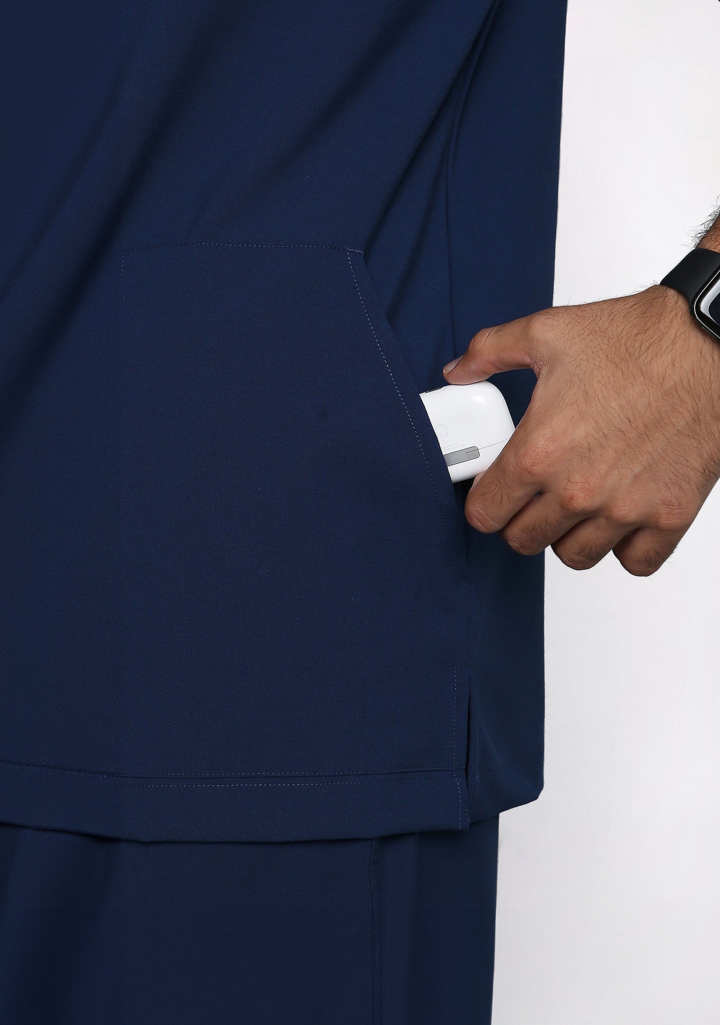 Close-up of the Knya scrub top's chest pocket holding an earbud case