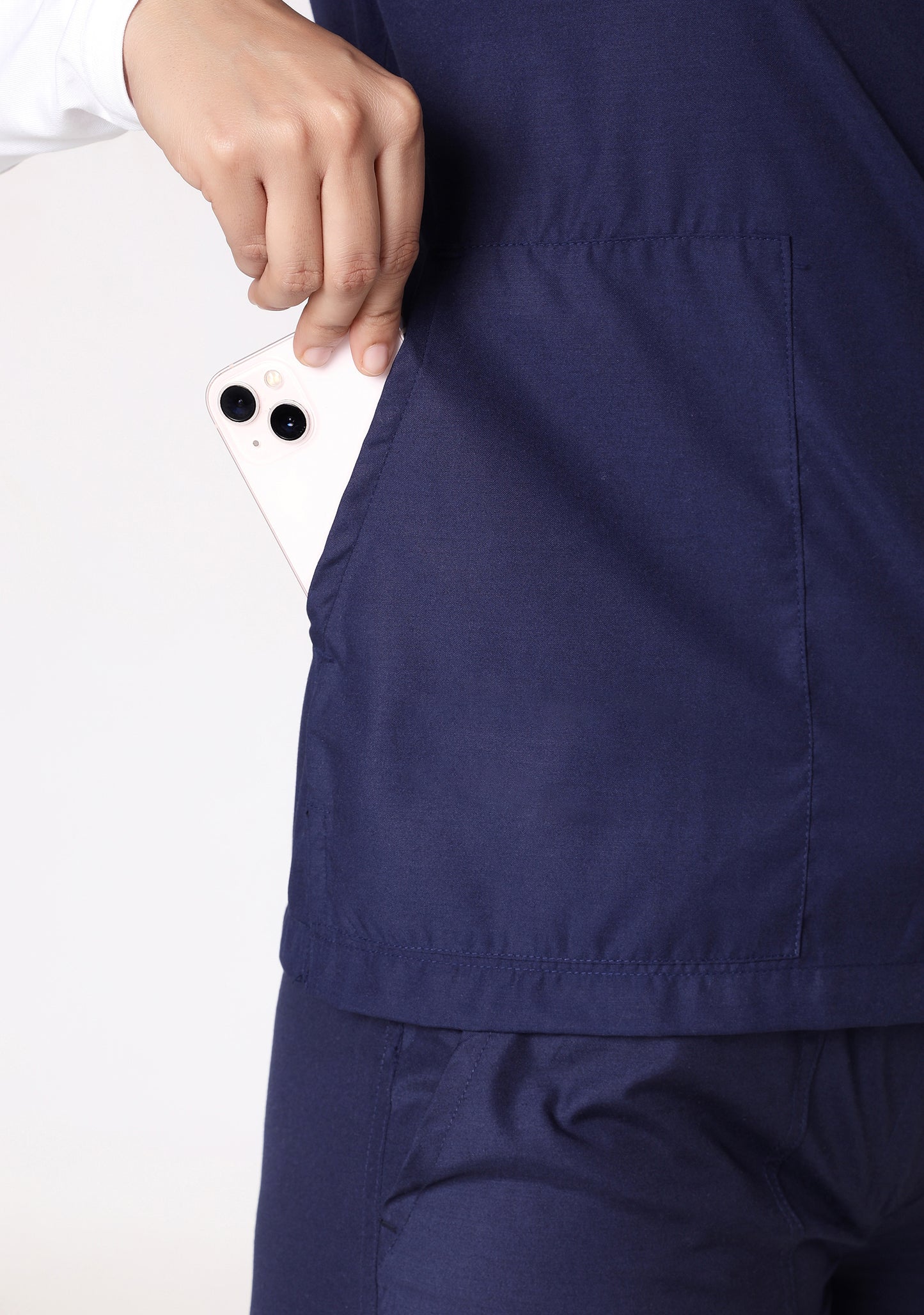 Close-up of a smartphone being placed in the Knya scrub top's pocket.