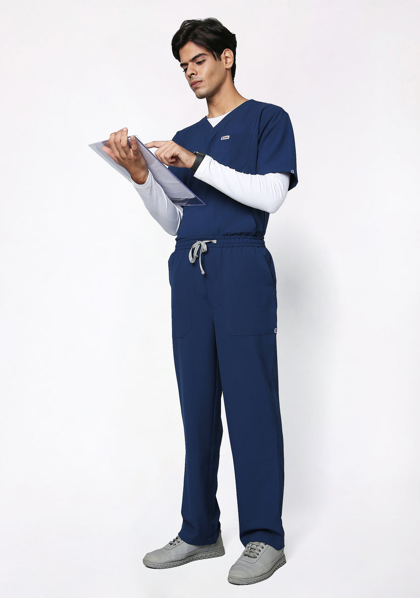 Model in Knya Ecoflex navy blue scrubs reviewing a clipboard